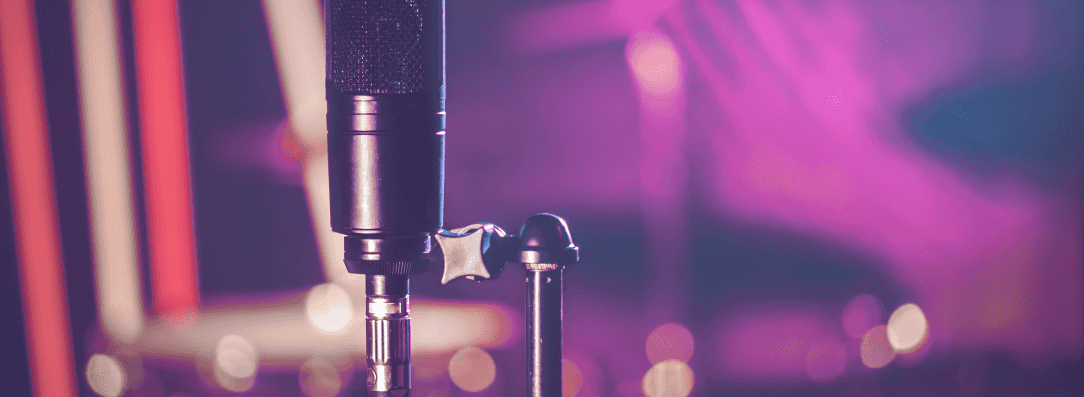 Close up of a microphone on a boom stand. Blurred background of a studio environment.