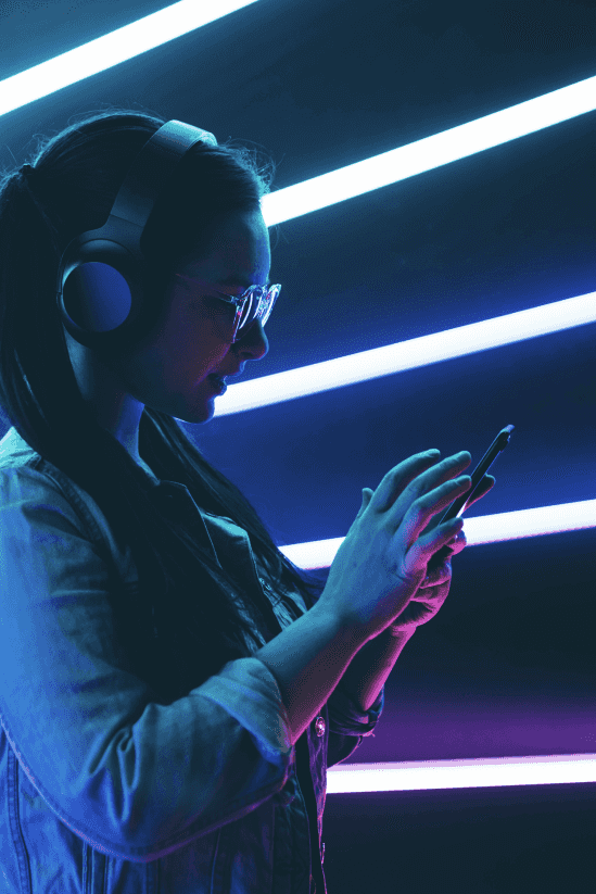 Girl with white headphones and glasses typing on her phone