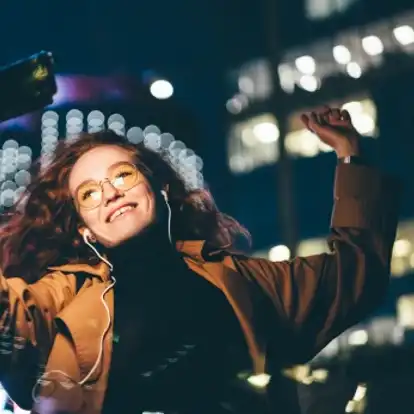 Dancing happy girl listening on her mobile phone with ear buds t her favourite artists